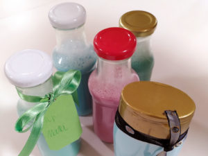 Glasflaschen und Duschgelflasche befüllt mit buntem selbstgemachtem Duschgel